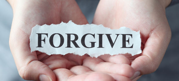 Trozo de papel roto con la palabra "Perdonar" en las palmas de las manos de la mujer.