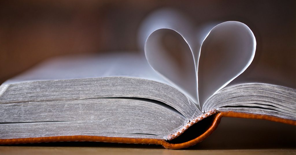 Foto de um livro, posiblemente la Biblia, com um corazón hecho con dos pages.