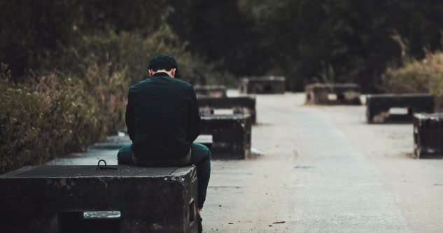 Hombre sentado no banco de concreto solo