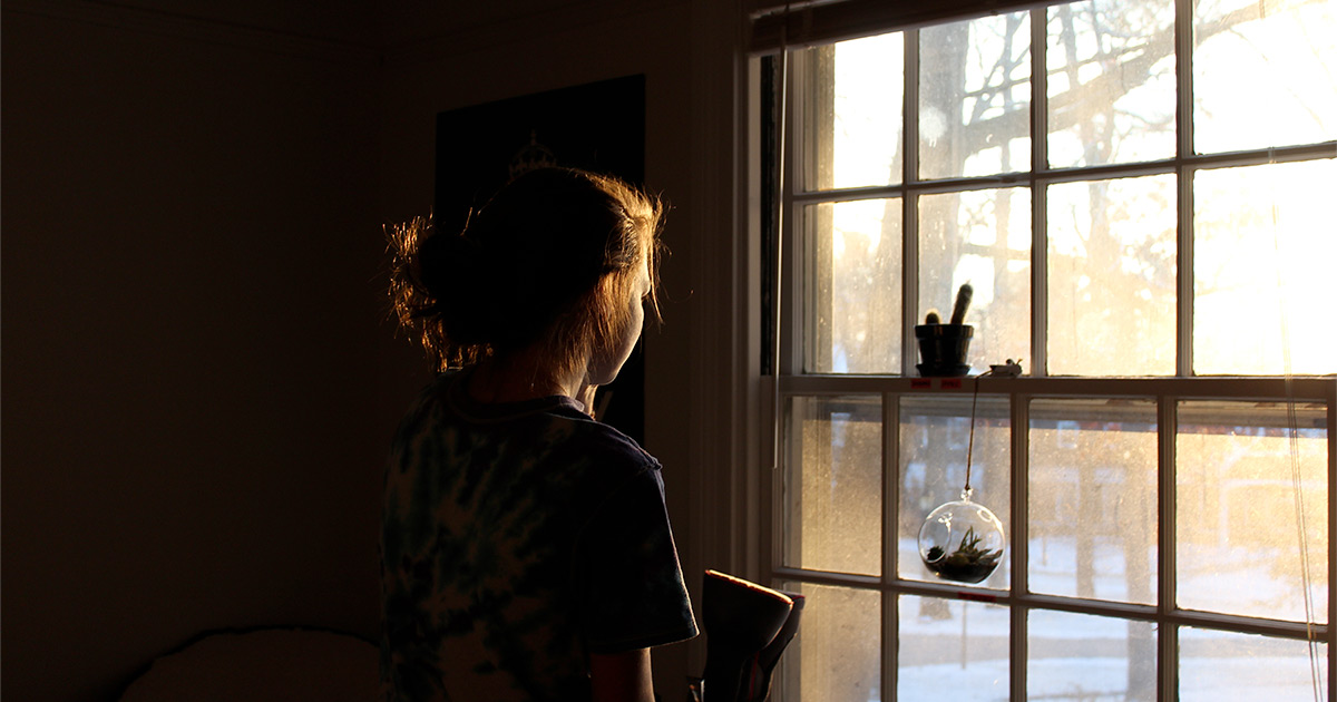 Chica femenina junto a la ventana mirando por la ventana